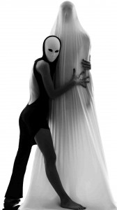 Schwarze Figur mit Maske hält Person unter einem weißen Laken fest, bedrohlich