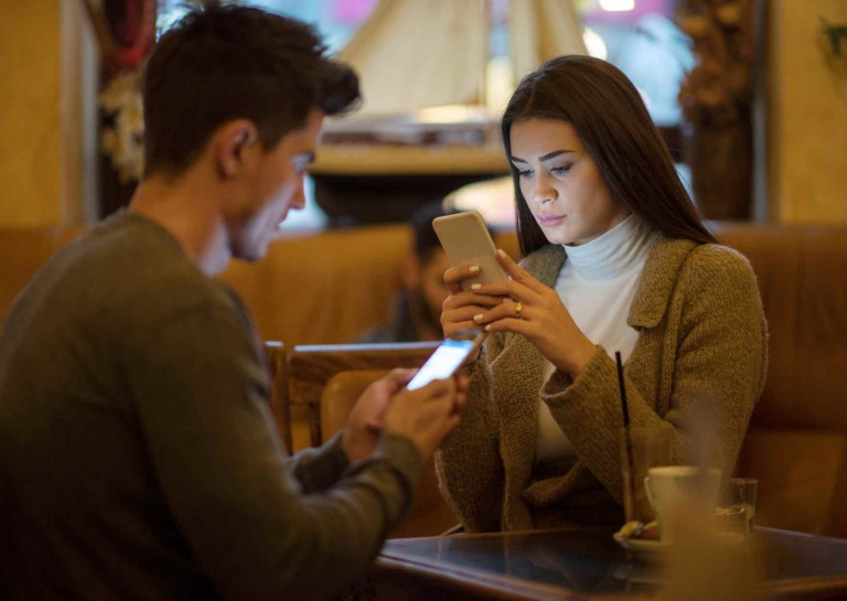 Generation X und Y, zwei Jugendliche am Tisch, starren beide in ihr Handy anstatt sich zu unterhalten